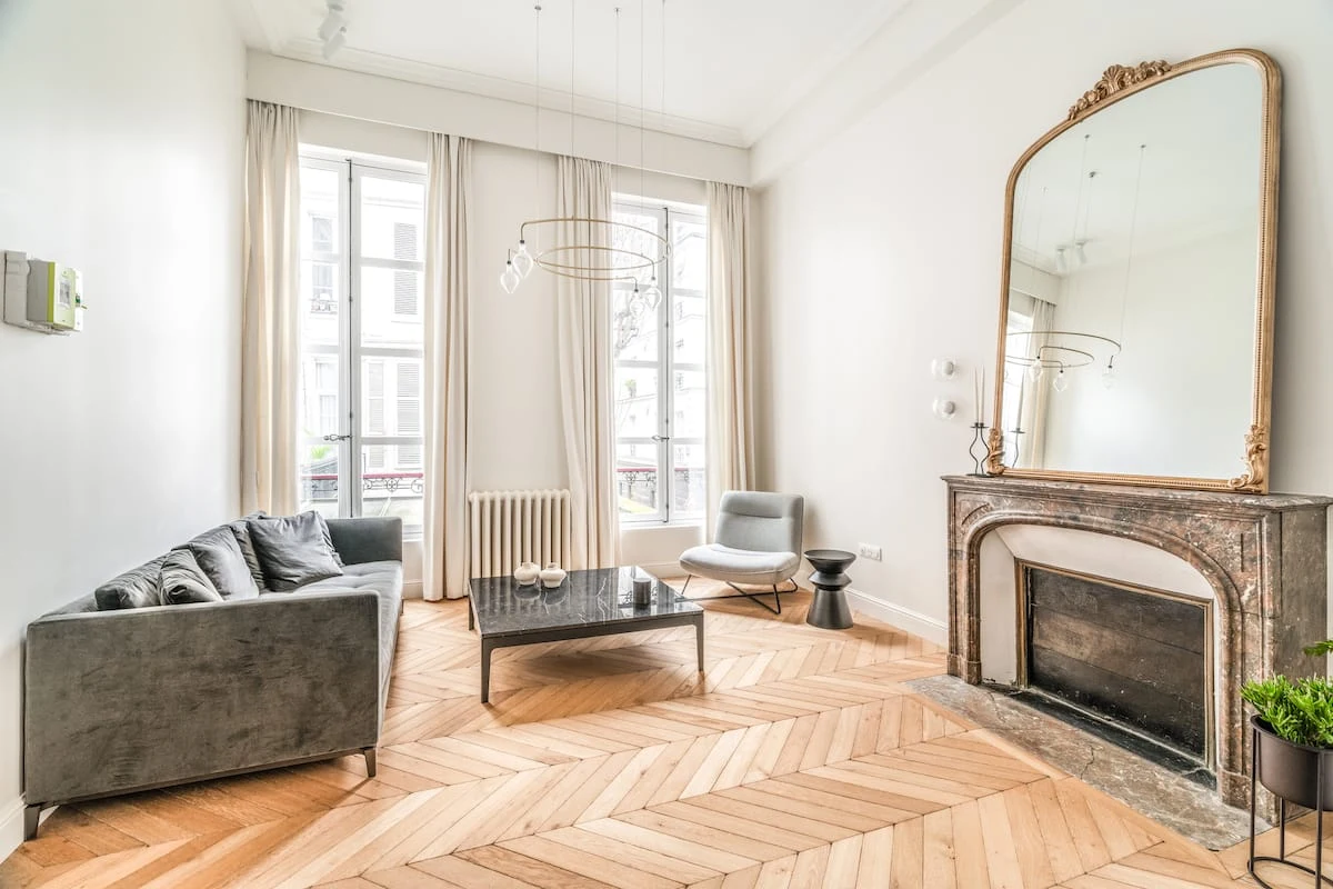 Salon lumineux de l’appartement Louvre–Rivoli, parquet parisien et cheminée en marbre